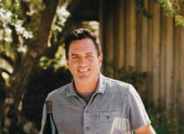 Winemaker Joe Nielsen holding a bottle and glass of Ram's Gate red wine.