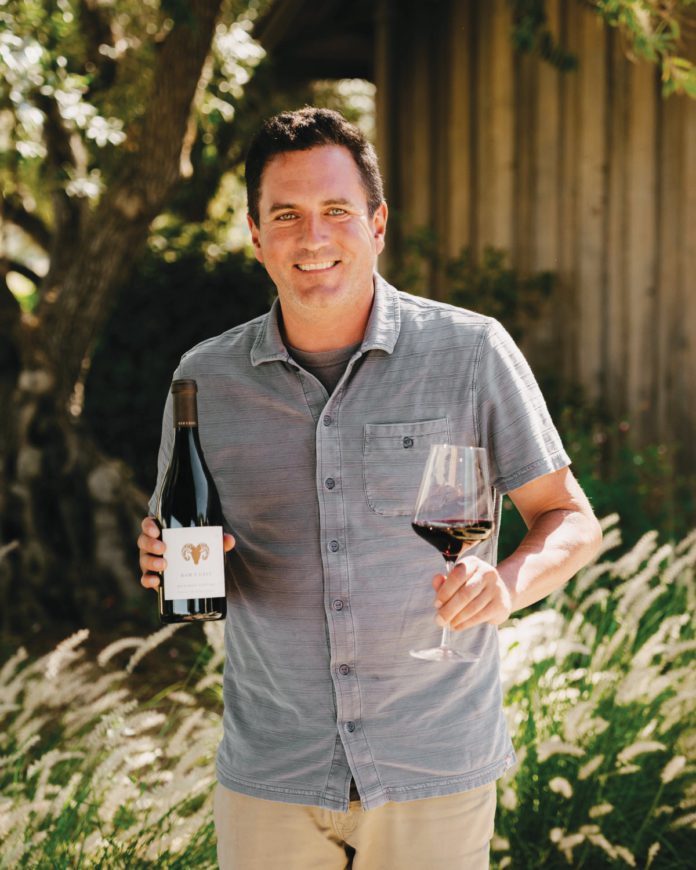 Winemaker Joe Nielsen holding a bottle and glass of Ram's Gate red wine.
