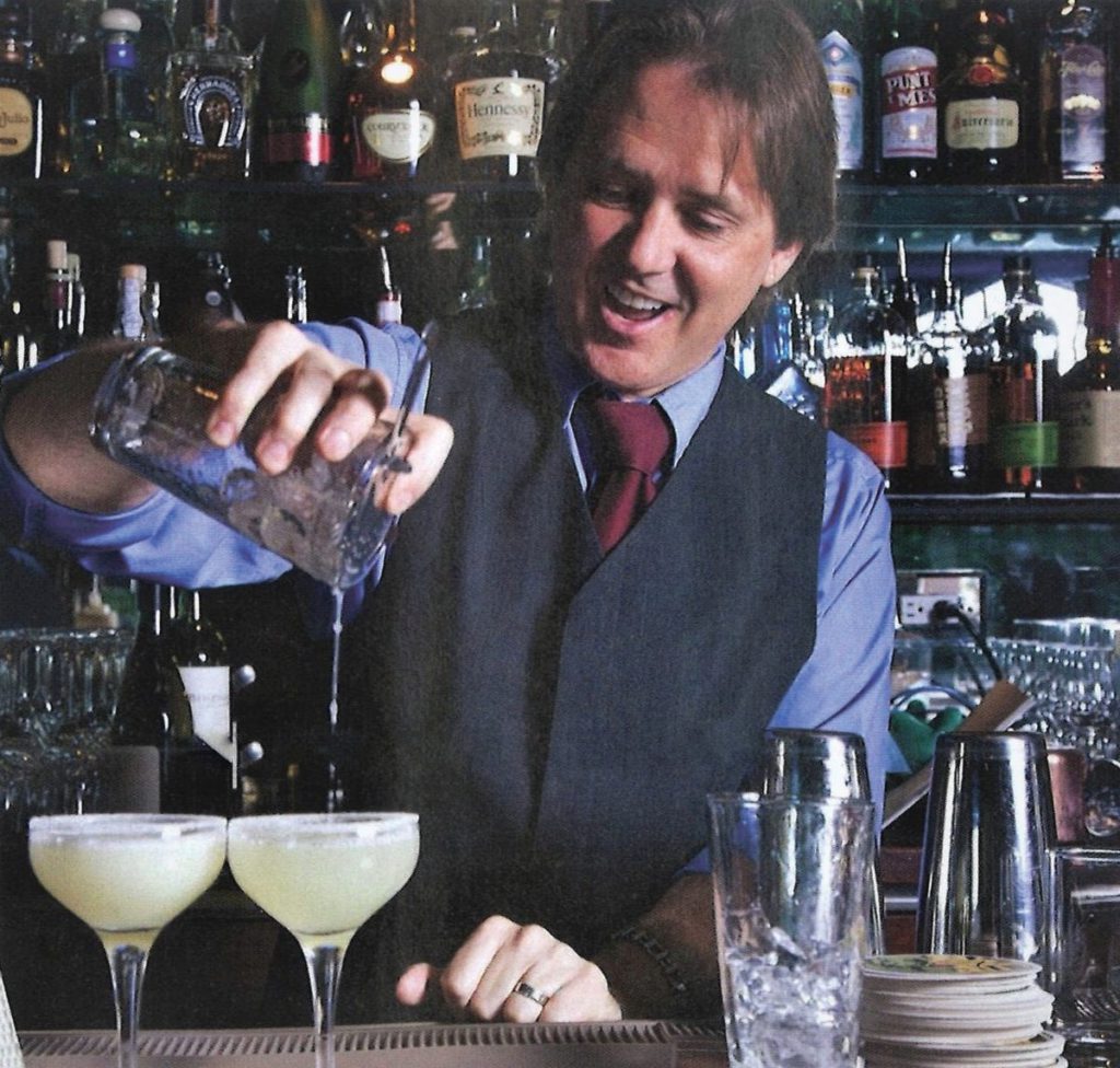 Barfly Jeff Burkhart stands behind the bar mixing drinks.