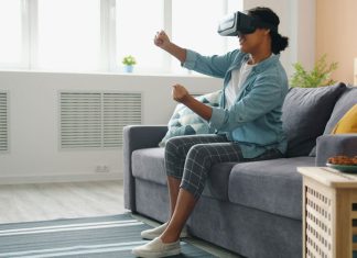 A person wearing a VR headset, sitting on a couch and interacting with the virtual environment