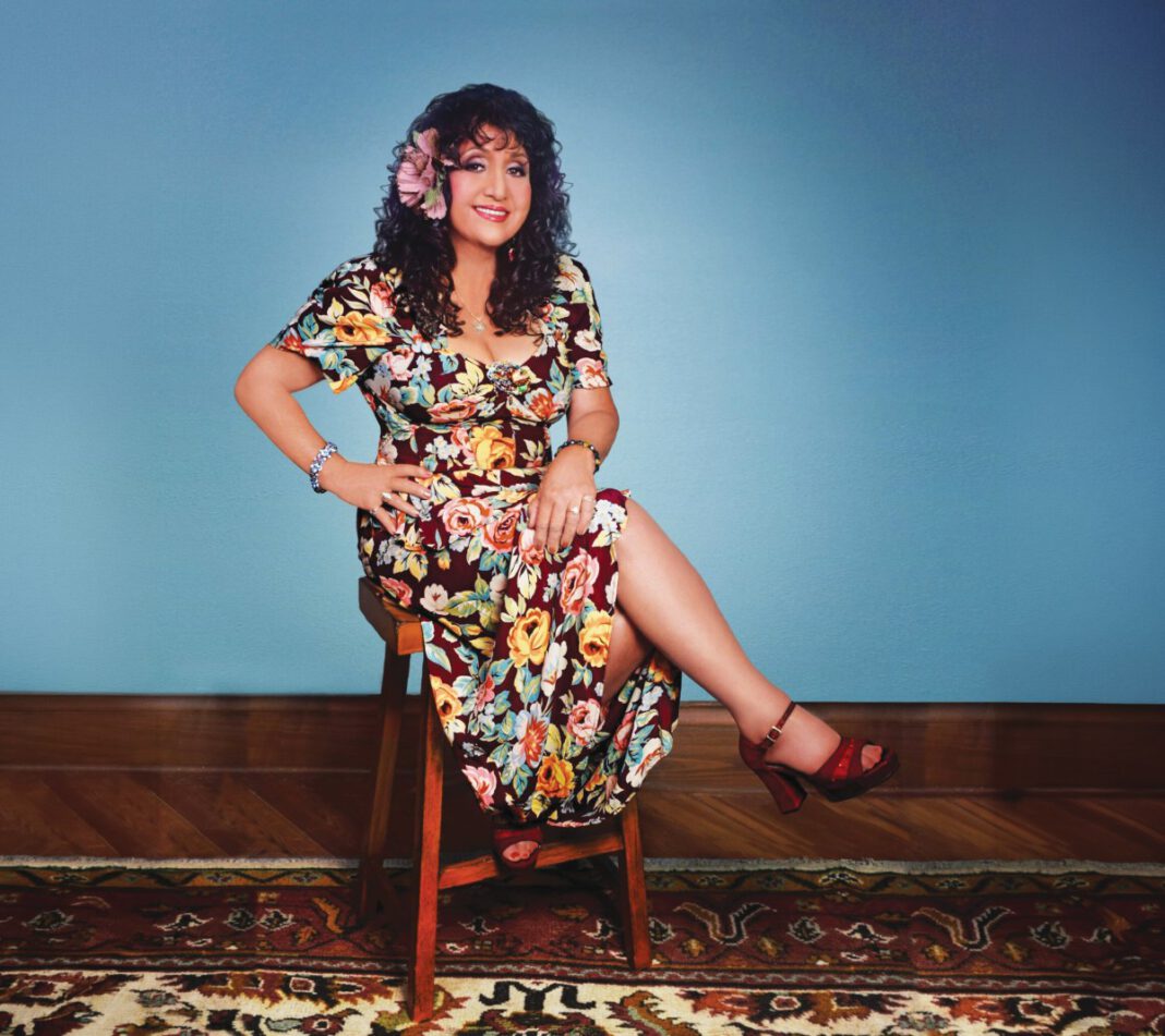 Maria Muldaur sitting on a stool.
