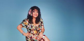 Maria Muldaur sitting on a stool.