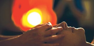 Person with eyes closed receiving a facial massage.