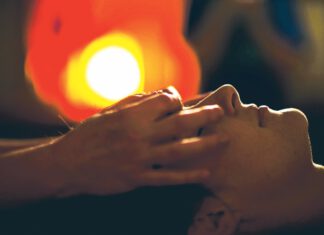 Person with eyes closed receiving a facial massage.