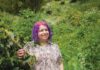 Devorah Freudiger standing in front of green shrubbery.