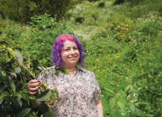 Daily Grind: Devorah Freudiger’s Coffee Connection Devorah Freudiger standing in front of green shrubbery.