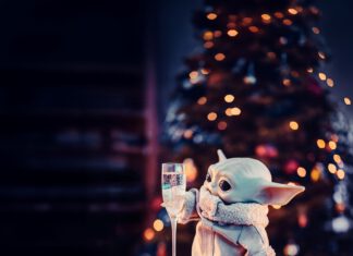 Grogu from Star Wars holding a glass of wine.