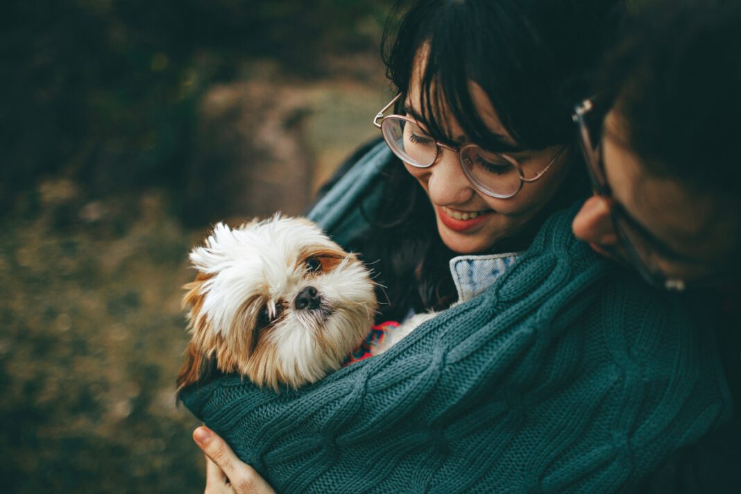 Woman holding a small dog outdoors.
