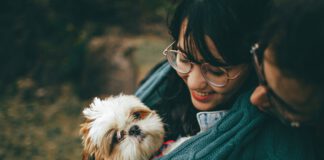 Woman holding a small dog outdoors.