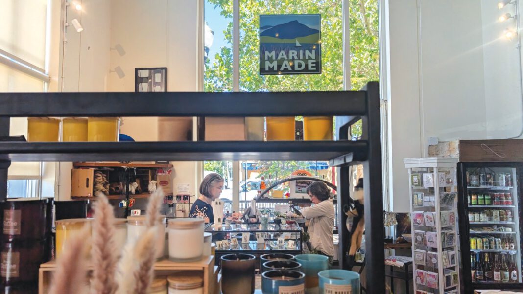 Shop manager assisting a customer inside a retail store filled with locally made products.