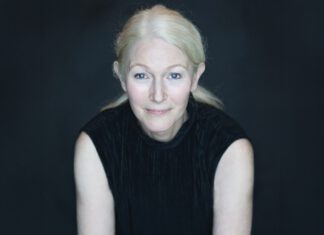 Marin author Nina Schuyler against a black background, with her blond hair pulled back and wearing a black sleeveless top.