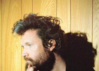 Father John Misty Headlines ‘Sound Summit’ Father John Misty in a red shirt and black jacket.