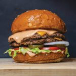 Burger Bash: Bay Area Burger Week Back on the Menu A double-patty cheeseburger with melted cheese, pink sauce, lettuce, tomato, pickles and onion on a sesame bun.