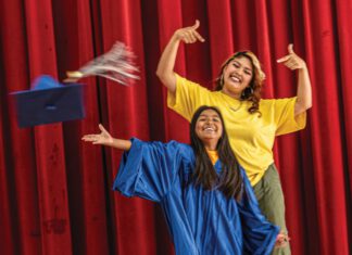 Higher Calling: The Hannah Project Bets Big on Marin City Kids A smiling girl wearing a blue graduation gown throws her cap into the air while a smiling woman in a yellow shirt stands behind her gesturing.